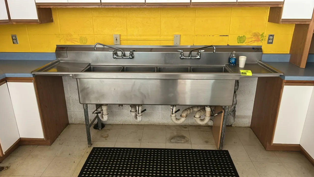 Eagle 4-compartment stainless steel sink. Features left and right drainboards, two splash-mount swivel faucets, and lever-actuated waste drains. Dimen