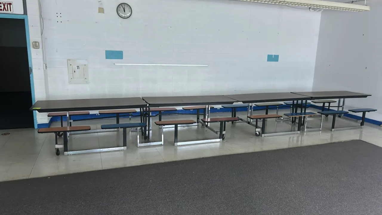 Laminate mobile folding cafeteria tables. Features woodgrain laminate tops, integrated bench-style stool seats in blue, brown, and red, and folding me