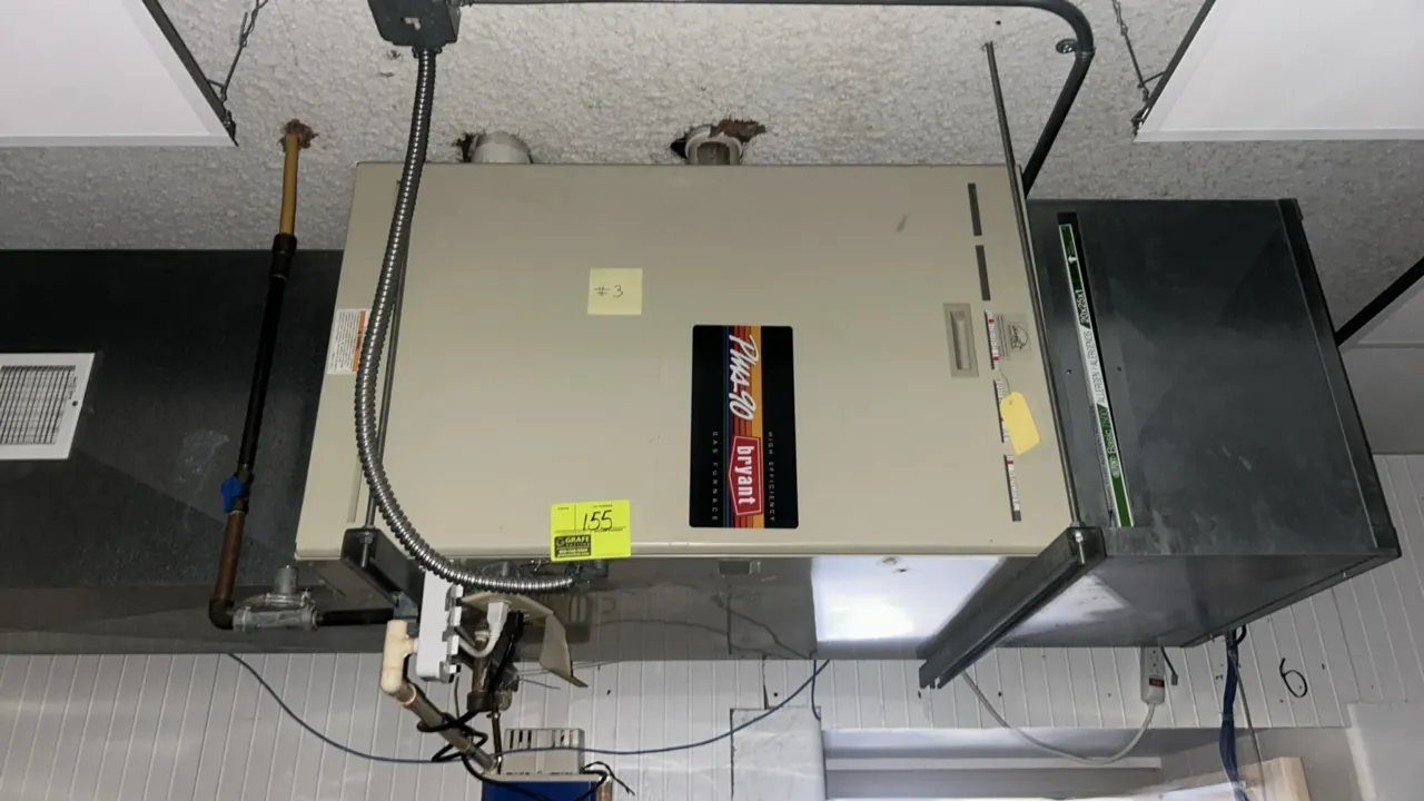 Bryant Plus 90 gas furnace. Features a high-efficiency design. Mounted on a ceiling-suspended metal support frame. Note: Connected ductwork, gas pipin