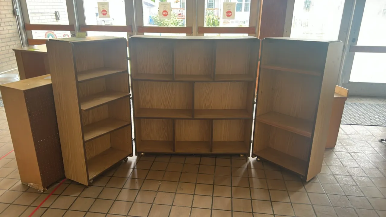 Foldable portable laminate cabinet. Features a wood grain laminate finish, a central shelving section with eight compartments, and two hinged side sto
