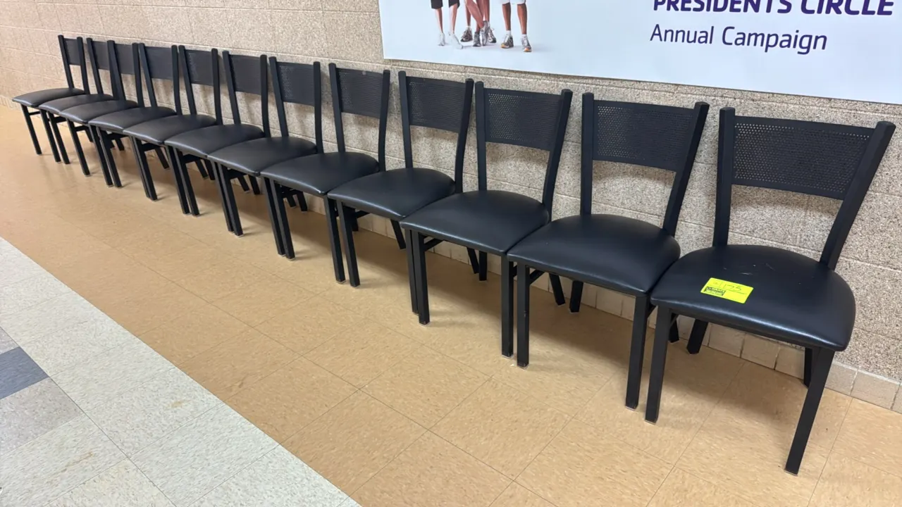 Metal padded chairs. Features black metal frames, perforated metal backrests, and padded black vinyl seats.
