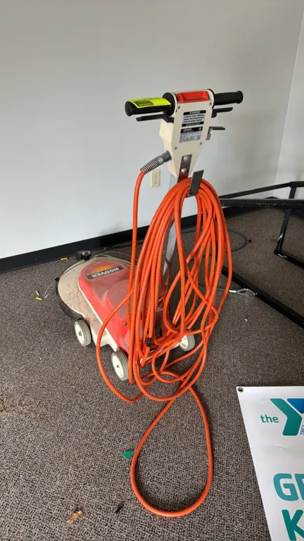 Hoover C5039 FloorMax 1550 electric floor polisher. Features a dual-handle grip design, integrated cord wrap with orange power cord, and front-mounted