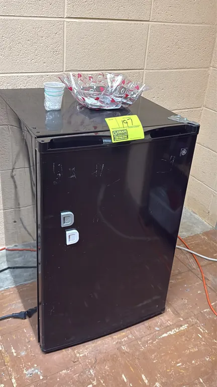 GE compact refrigerator. Features a black exterior finish, adjustable interior glass shelving, and integrated door storage bins. Includes an upper chi