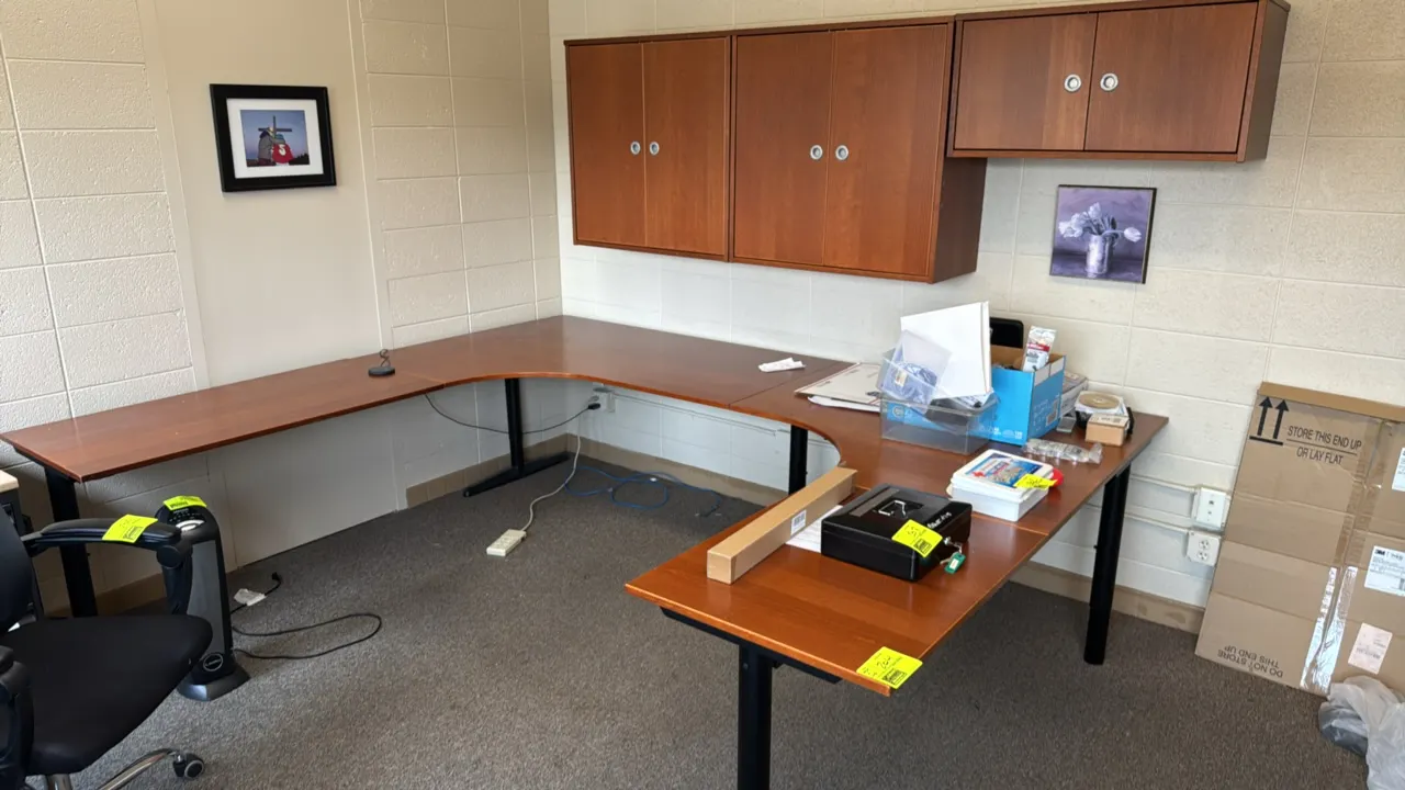 Laminated wood U-shape desk. Features a cherry-style finish and black metal T-leg bases. Includes three matching wall-mounted upper cabinets with doub