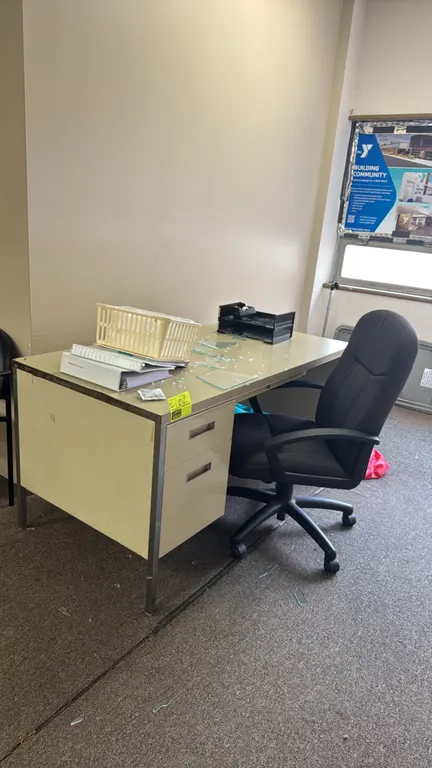 Metal desk with chair and office supplies. Features a single-pedestal desk with two drawers and a laminate top, measuring 6'L. Includes a black fabric