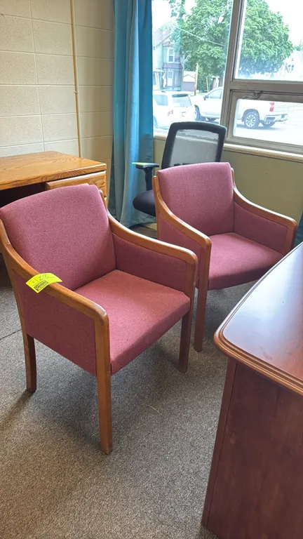 Wood-framed padded upholstered armchairs. Features mauve fabric upholstered seats, backrests, and side panels. Supported by solid wood frames with int