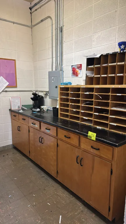 9'L wood counter with contents. Features a black laminate countertop, six drawers, and three double-door lower storage cabinets. Includes two wooden d