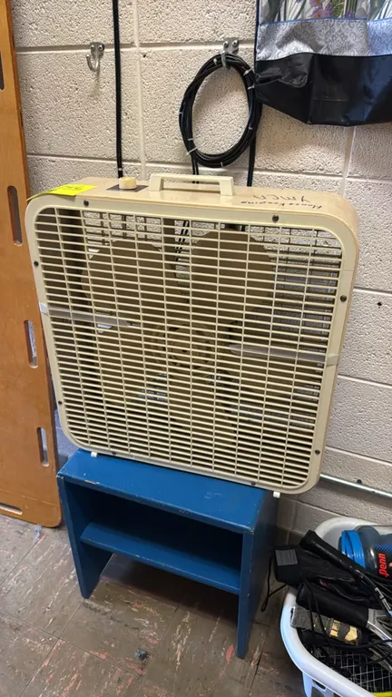 Unbranded metal box fan. Features a top rotary control knob, plastic safety grilles, and an integrated carrying handle. Includes a blue-painted wooden