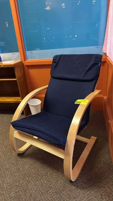 Wood padded lounge chair. Features a curved bentwood frame with a navy blue padded fabric cushion. Designed with integrated armrests on a cantilevered