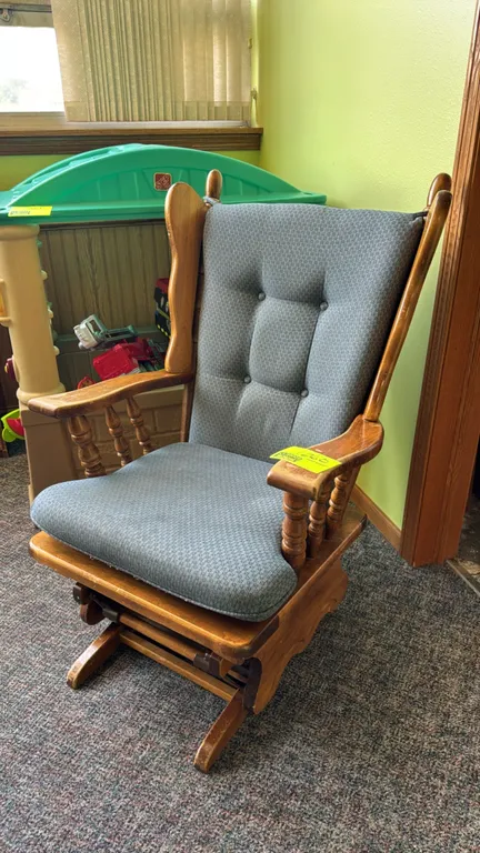 Wood glider rocking chair. Features a wingback-style frame with spindle arm supports and button-tufted blue patterned upholstered back and seat cushio