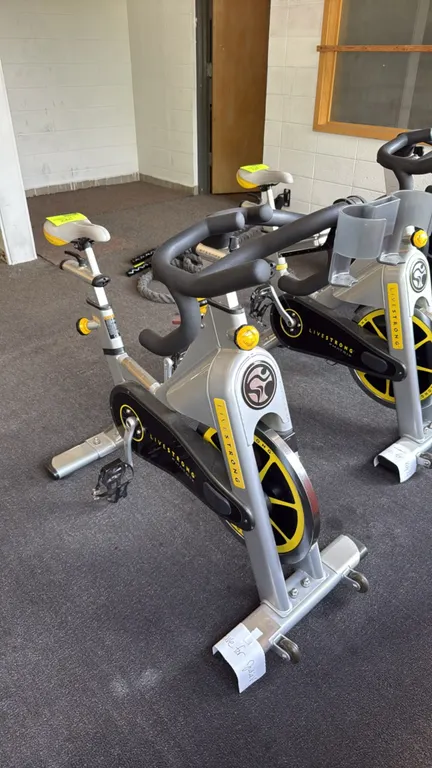 Matrix Livestrong indoor cycling exercise bicycle. Features an adjustable seat and handlebars, manual resistance control knob with emergency brake, an