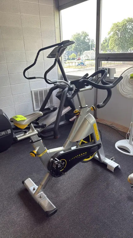 Matrix Livestrong exercise bicycle. Features an adjustable seat and handlebars, manual tension adjustment knob with integrated brake, and a digital di