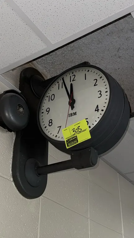 A Vintage IBM Double-Sided Wall-Mounted Clock. (IBM, circa 1950s) A classic industrial clock featuring two white clock faces with black Arabic numeral