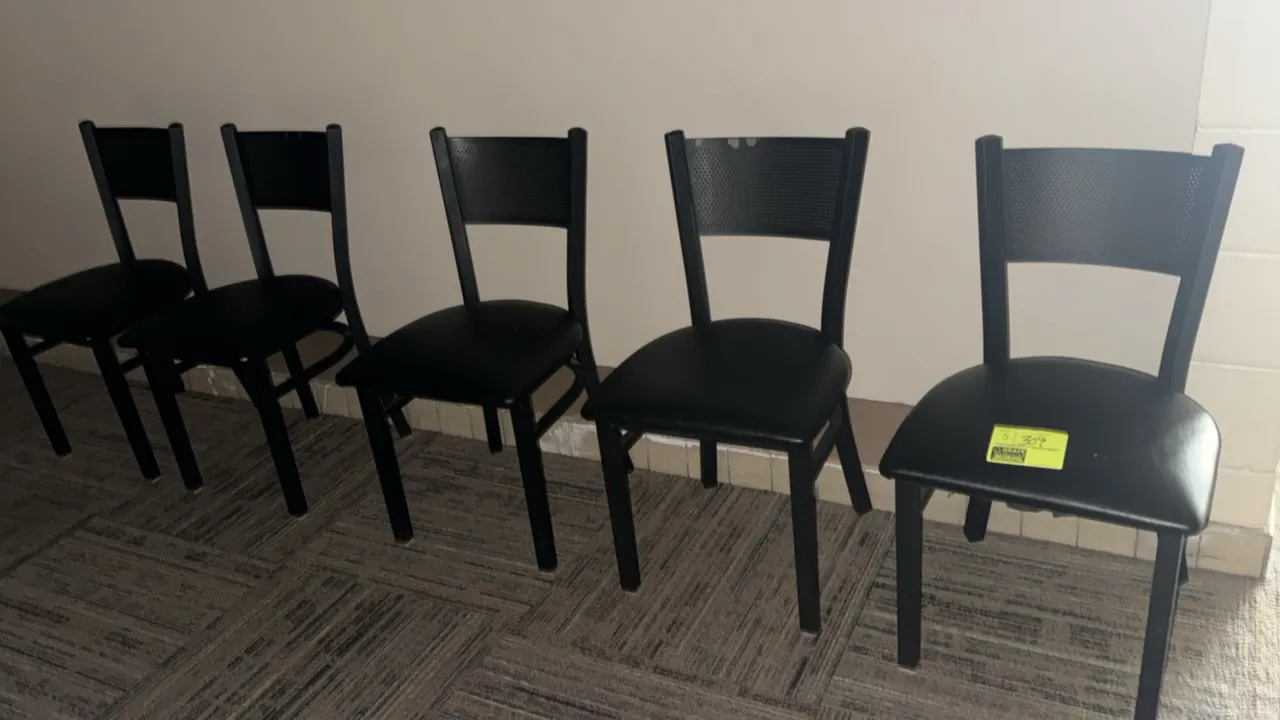 Black metal chairs. Features padded black vinyl seats, curved perforated backrests, and welded steel frames.