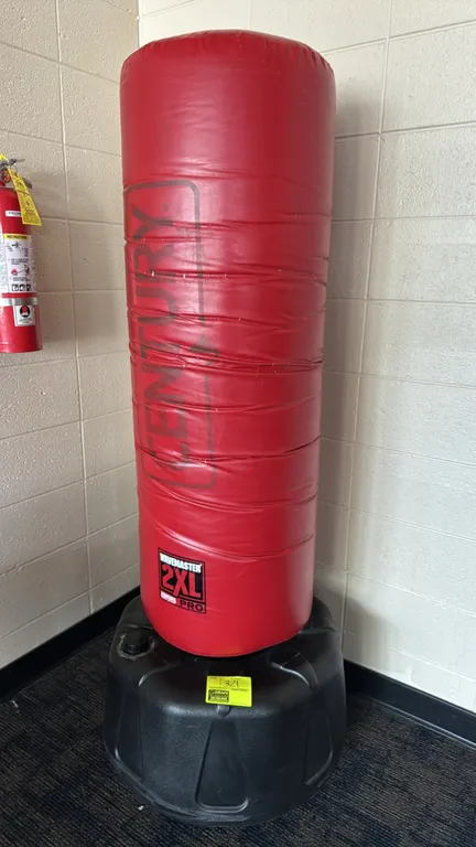 Century WaveMaster 2XL Pro freestanding sparring bag. Features a high-density foam core with a red vinyl cover. Mounted on a fillable black plastic ba