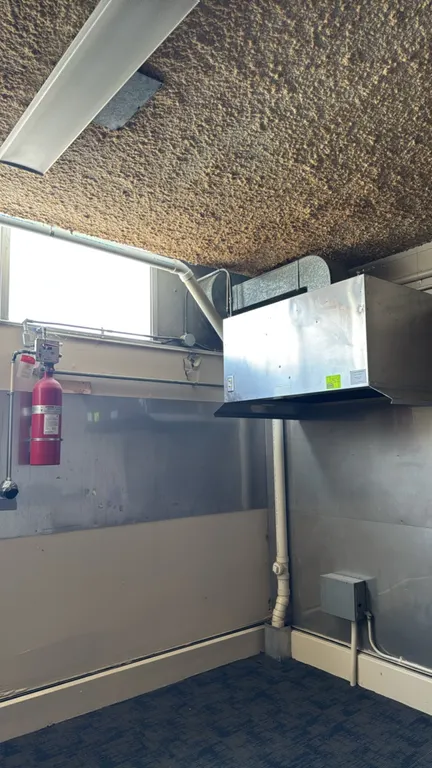 Stainless steel exhaust hood. Features integrated Kidde Sentinel fire suppression system with wall-mounted chemical cylinder and nozzles. Dimensions: