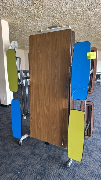 SICO mobile folding cafeteria table with attached stool seating. Features a woodgrain laminate tabletop and individual blue and green stools. Collapsi