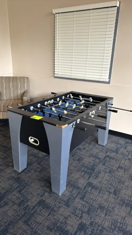 Barrington Billiards Company laminate foosball table. Features a blue playing field with black and cream-colored players, steel rods, and end ball ret