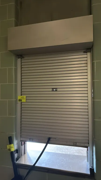 Aluminum roll-up security gate. Features a rolling slat design, side guide rails, and an overhead protective housing box. Designed for counter-top win