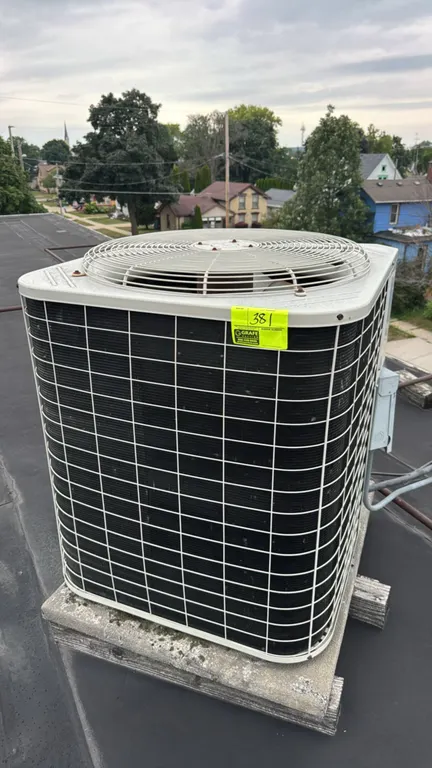 Bryant 561CJ060-A outdoor air conditioner condensing unit. Features a top-discharge fan and wire coil guard. S/N: 1799E22721. Refrigerant: R-22. Elect