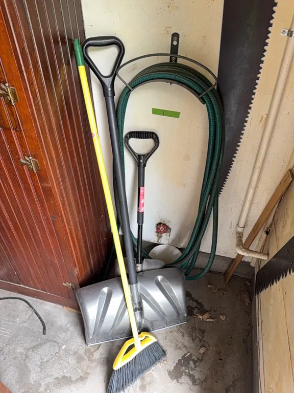 Garden hose and holder, shovels, broom. Note: does not include saw.