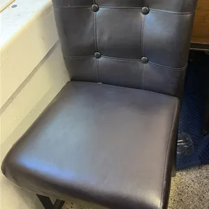 Black vinyl high-top chairs. Features padded, button-tufted backs and upholstered seats. Mounted on dark-finished wood legs with stretchers. 25" seat 