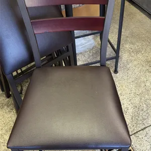 Metal folding chairs. Features padded black vinyl seats, wood-finish ladder backs, and brown metal frames. Designed to fold for convenient storage.