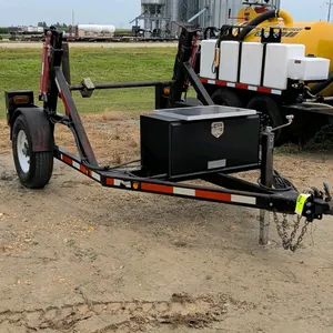Custom hydraulic lift reel trailer. Features dual hydraulic lift cylinders, a spindle reel bar, and a tongue-mounted black toolbox with an integrated 