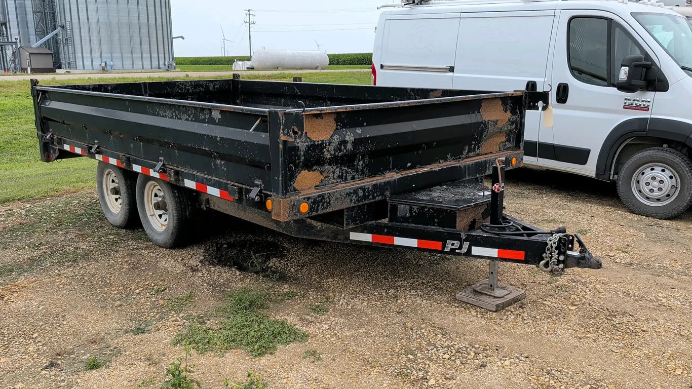 PJ Trailers dump trailer. Features 19"H sidewalls, hold-down sides, and a rear gate that swings up or double-splits swing-out. Equipped with twin axle