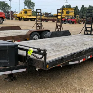 PJ bumper hitch twin-axle flatbed trailer. Features a wood deck, beaver tail, (2) fold-up ladder ramps, and a tongue-mounted polymer toolbox. Dimensio