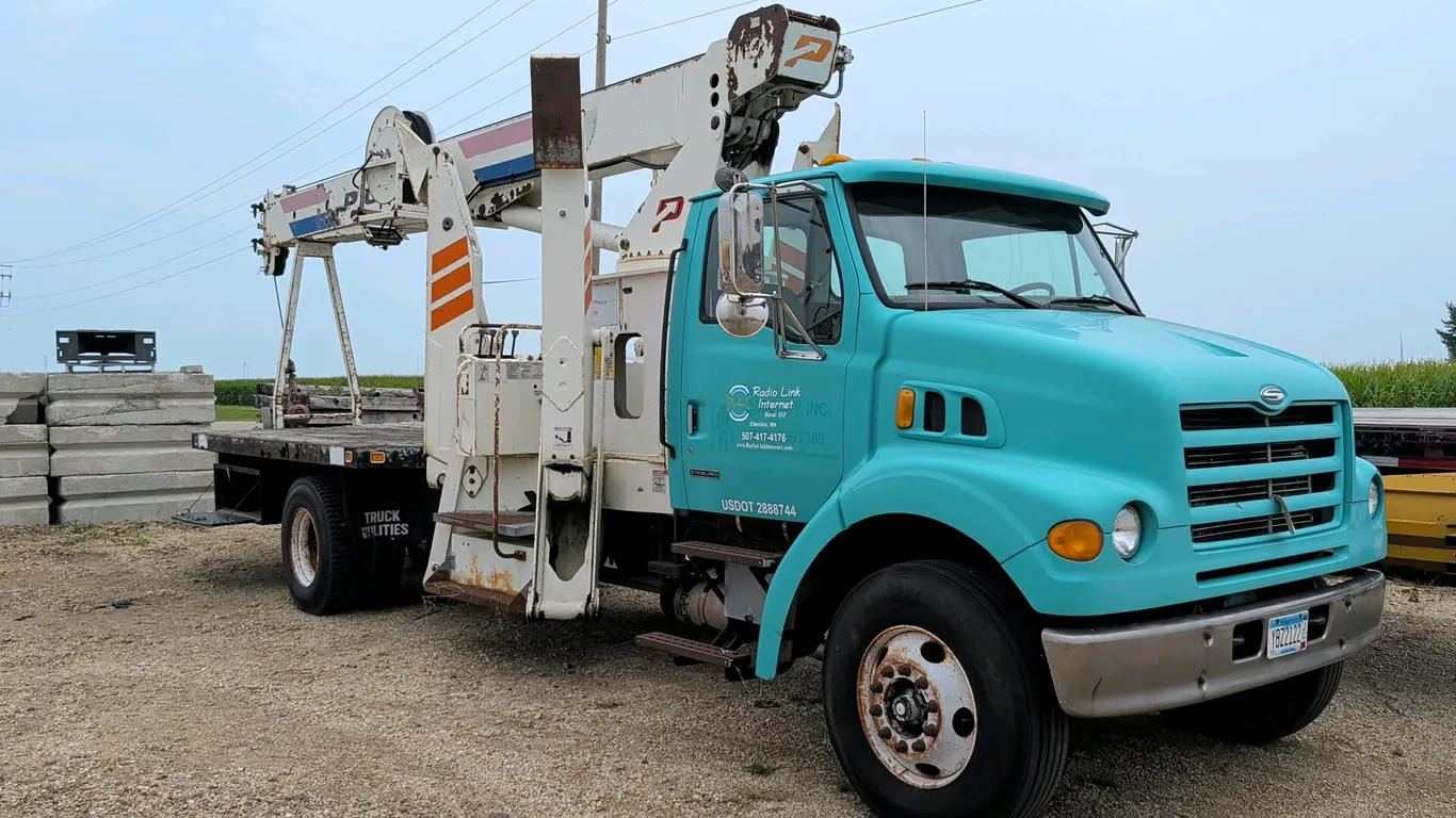 2000 Sterling flatbed crane truck. Features a Pioneer Series 1000 crane, 4 outriggers, 6-speed manual transmission, and wood deck flatbed. Showing 27,