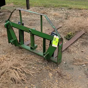 Loader-mount forklift attachment. Features adjustable pallet forks and a green steel frame with an integrated safety guard. Equipped with John Deere s