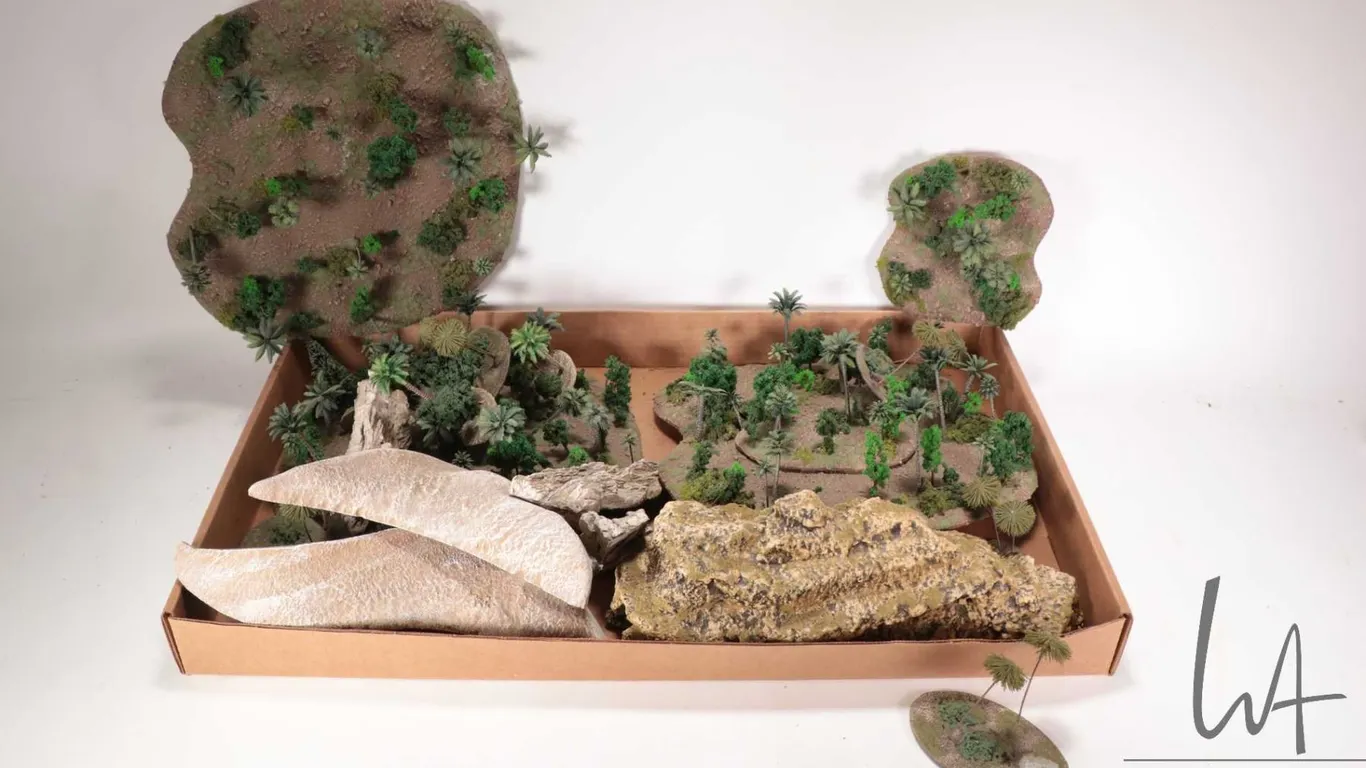 Large selection of tabletop gaming terrain including small forests, rubber rock formations, sandy te