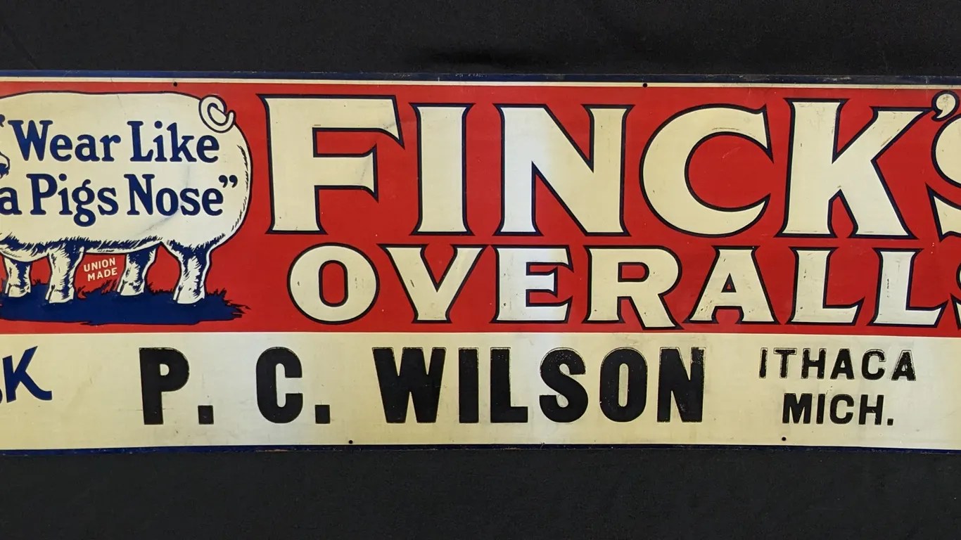 EMBOSSED TIN SIGN FINCK'S OVERALLS "WEAR LIKE A PIGS NOSE" ASL P.C. WILSON ITHACA MICHIGAN