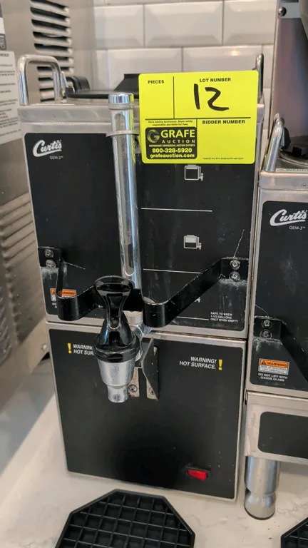 Curtis GEM-3 coffee dispenser with warming stand. Features front dispensing faucet, faucet guard, liquid level sight gauge, top carrying handles, and