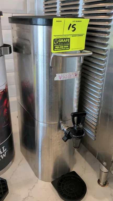 Stainless steel beverage dispenser. Features front lever dispensing faucet, front and rear carrying handles, removable black plastic lid, and drip tra