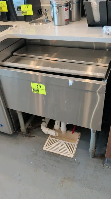 Stainless steel ice well. Features a sliding stainless steel cover and center drain. 30"W. Mounted on tubular legs with adjustable bullet feet. Conten