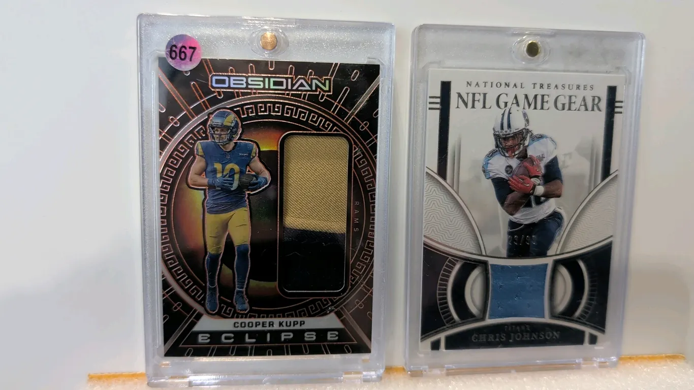 A Pair of Panini Football Memorabilia Cards. (Panini, 2023) Includes a 2023 Panini Obsidian Eclipse Cooper Kupp card numbered 29/49 with jersey swatch