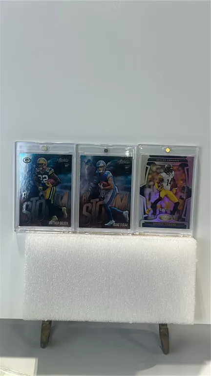 A Collection of 2025 Panini Football Cards. (Panini, 2025) A collection of (3) trading cards including a Matthew Golden Absolute "By Storm" RC, an Isa