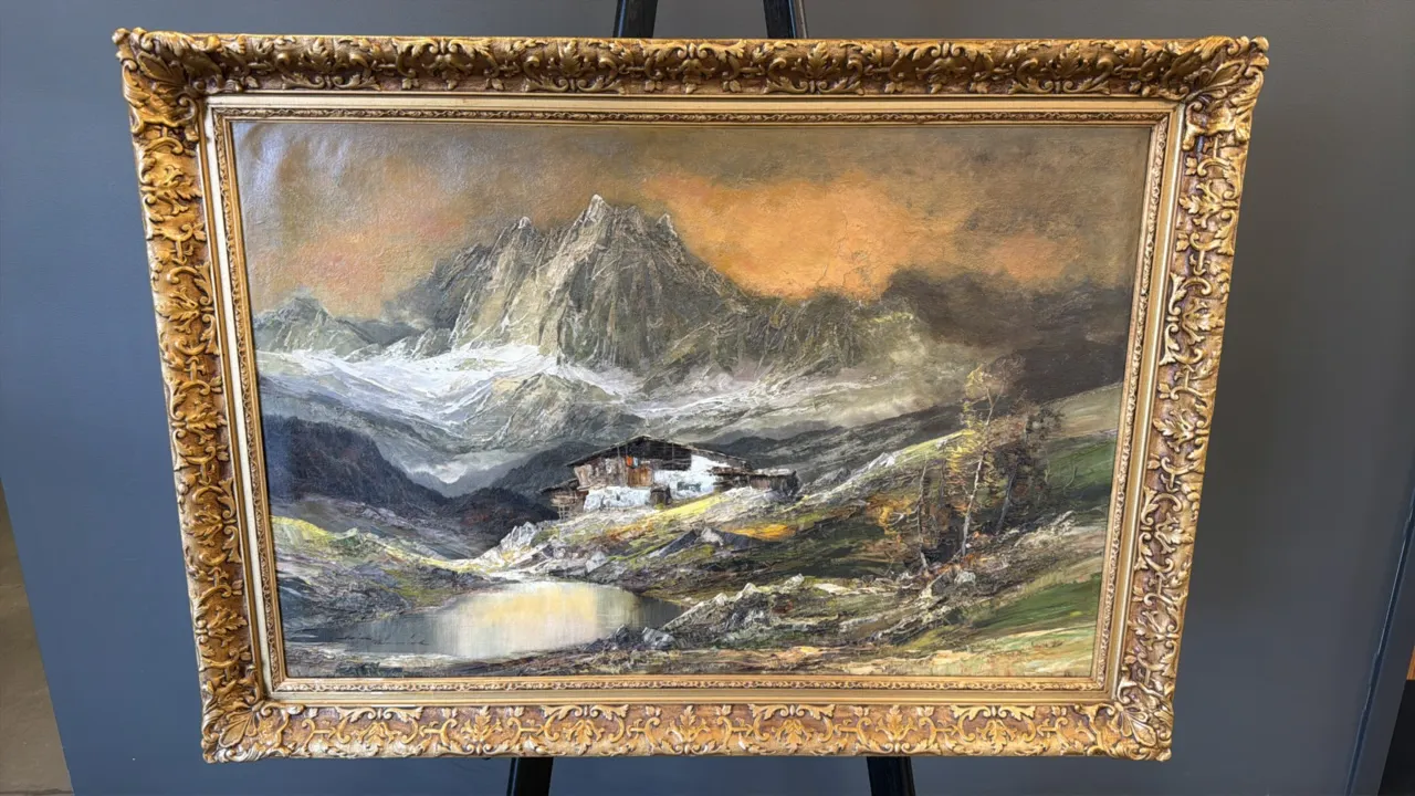 An Alpine Landscape Oil Painting. (Alois Arnegger) An original oil on canvas depicting a rustic chalet and glacial lake before snow-dusted Alpine peak