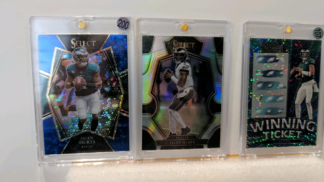 A Collection of (3) Jalen Hurts Trading Cards. (Panini, 2021-2023) Includes a 2021 Panini Select Premier Level No. 128 numbered 03/25, a 2022 Panini S