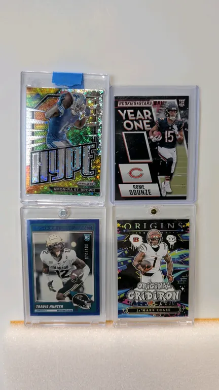 A Collection of Panini NFL Trading Cards. (Panini, 2022-2025) Includes 2022 Prizm Hype Amon-Ra St. Brown #H-13, 2024 Rookies & Stars Year One Rome Odu