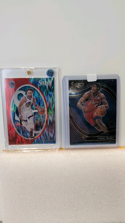 A Pair of Panini Select Basketball Cards. (Panini, 2020-2024) Includes a 2023-24 Stephen Curry "Select Certified" card numbered 56/99 (No. 4) in a mag