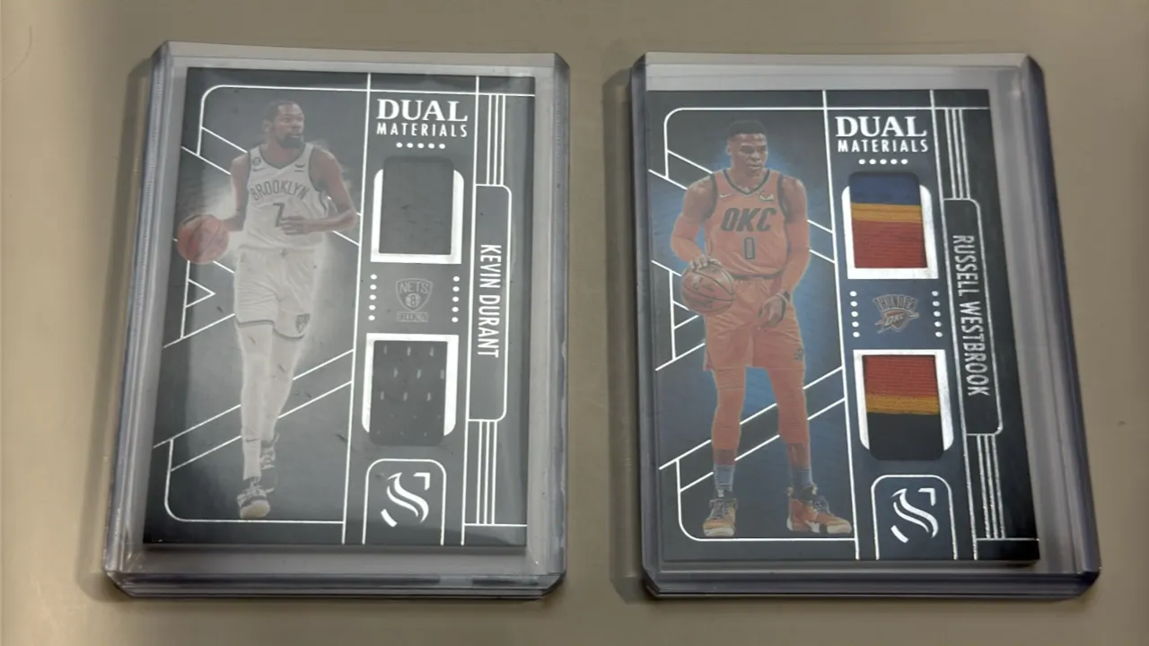 A Pair of Panini Silhouette Dual Materials Basketball Cards. (Panini, 2024-25) Includes Kevin Durant (No. DMA-DUR, Brooklyn Nets) and Russell Westbroo
