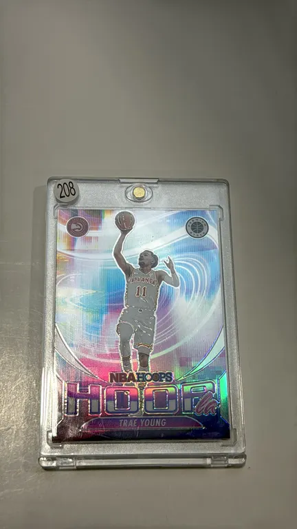A 2023-24 Panini NBA Hoops Premium Stock Trae Young Trading Card. (Panini, 2023-24) A "HOOPla" Prizm holographic trading card (No. 15) featuring Atlan