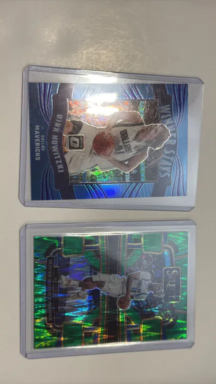 A Pair of Dallas Mavericks Basketball Cards. (Panini, 2023-24) Includes Dirk Nowitzki Donruss Optic "Winner Stays" insert (No. 4) and Olivier-Maxence