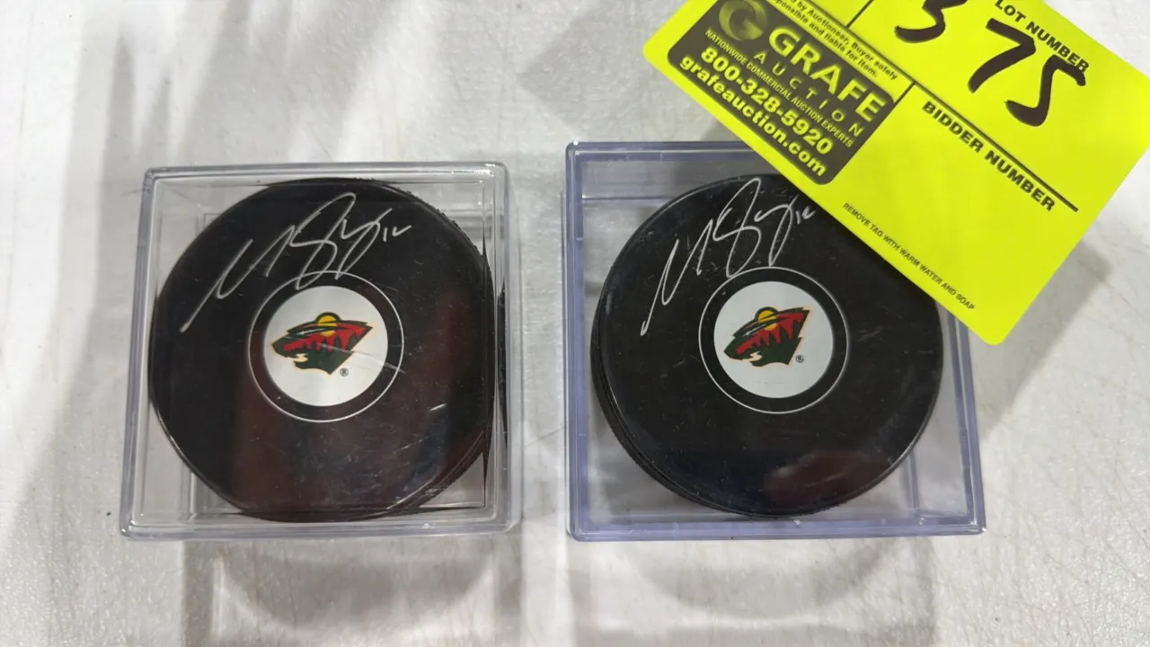 A Pair of Matt Boldy Autographed Minnesota Wild Hockey Pucks. Features silver-tone signatures on the front face above the Minnesota Wild team logo. Ea