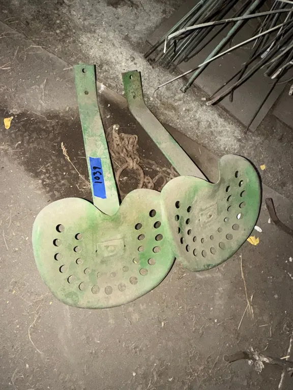 Two old metal tractor seats with brackets