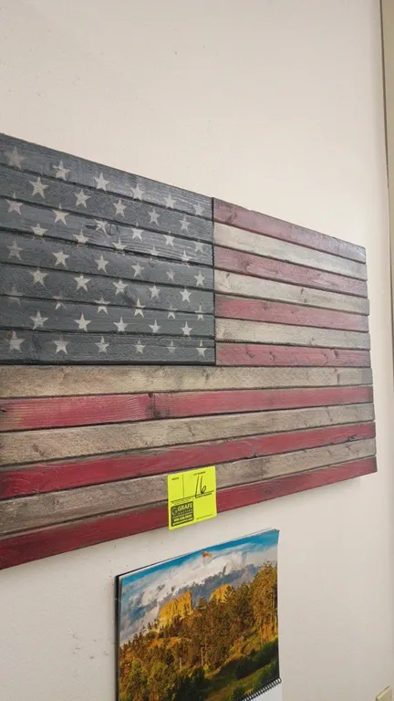 Wooden American flag wall art. Features rustic wood slat construction with a stained red, white, and blue finish with 50 stars. Dimensions: 35" x 19".