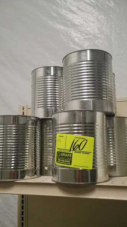 Assorted empty ribbed metal cans. Features unprinted silver-tone metal construction. Shelving and background items not included.